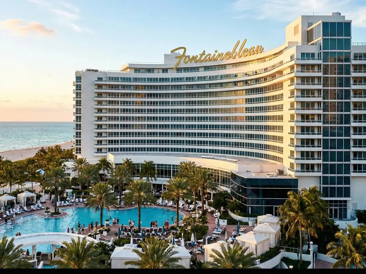 Exterior view of the iconic Fontainebleau Miami Beach hotel featuring its famous curved white architecture, palm trees, and luxury pool deck.